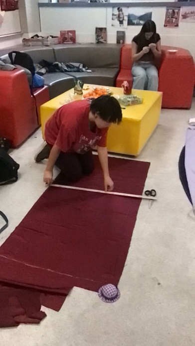 A person measuring a red carpet

Description automatically generated