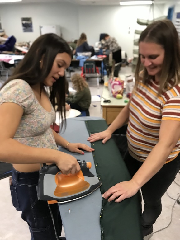 A person ironing a piece of fabric

Description automatically generated