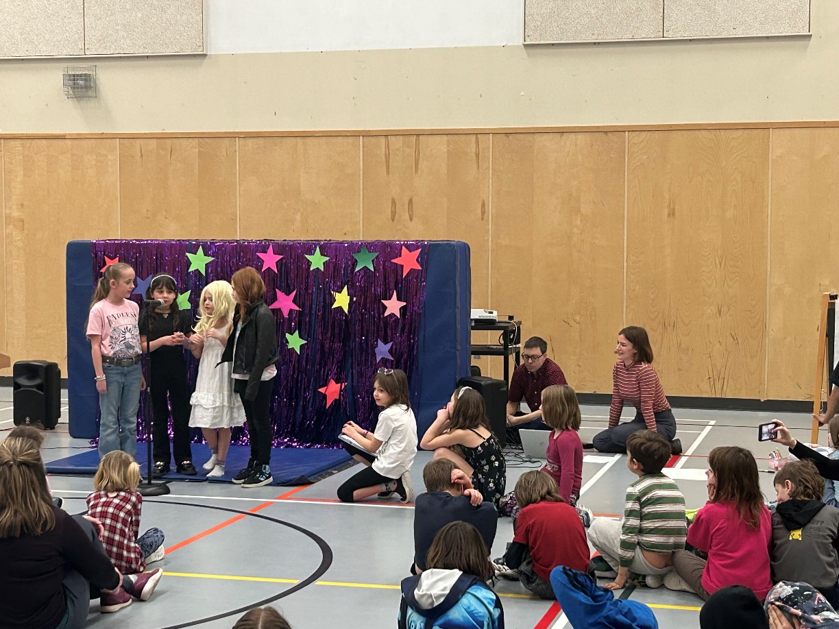 A group of children sitting on the floor in a room

Description automatically generated