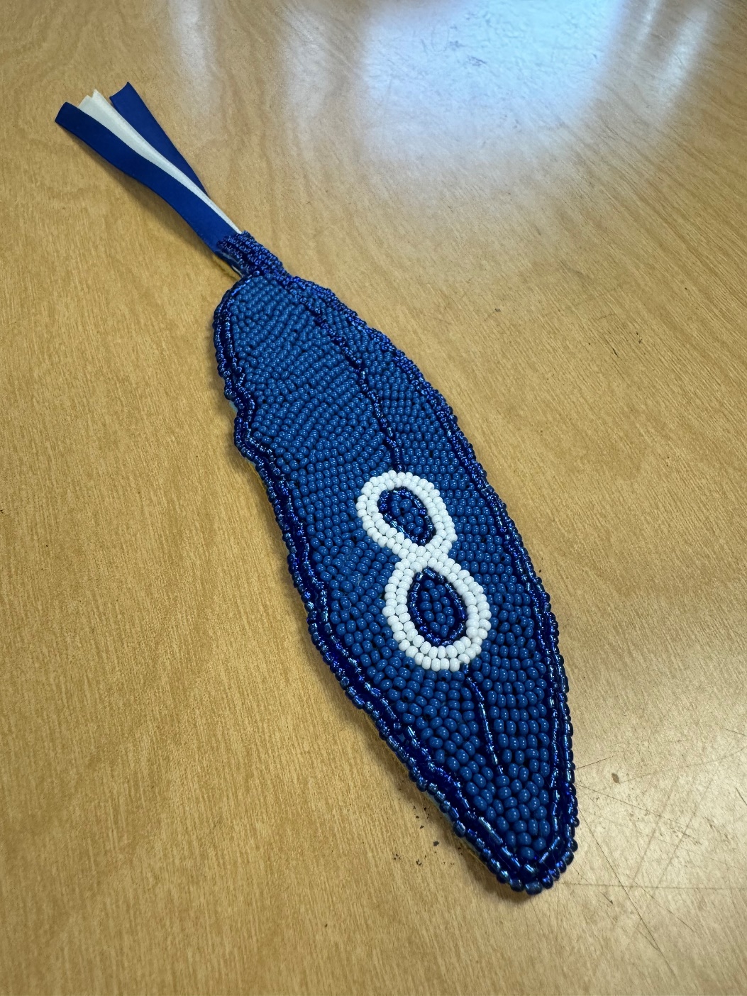 A blue beaded feather with a number on it

Description automatically generated