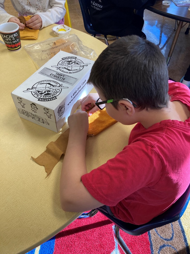 A child sitting at a table with a box

Description automatically generated