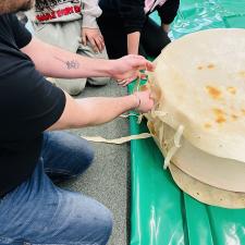 students adding the rawhide string to the drum